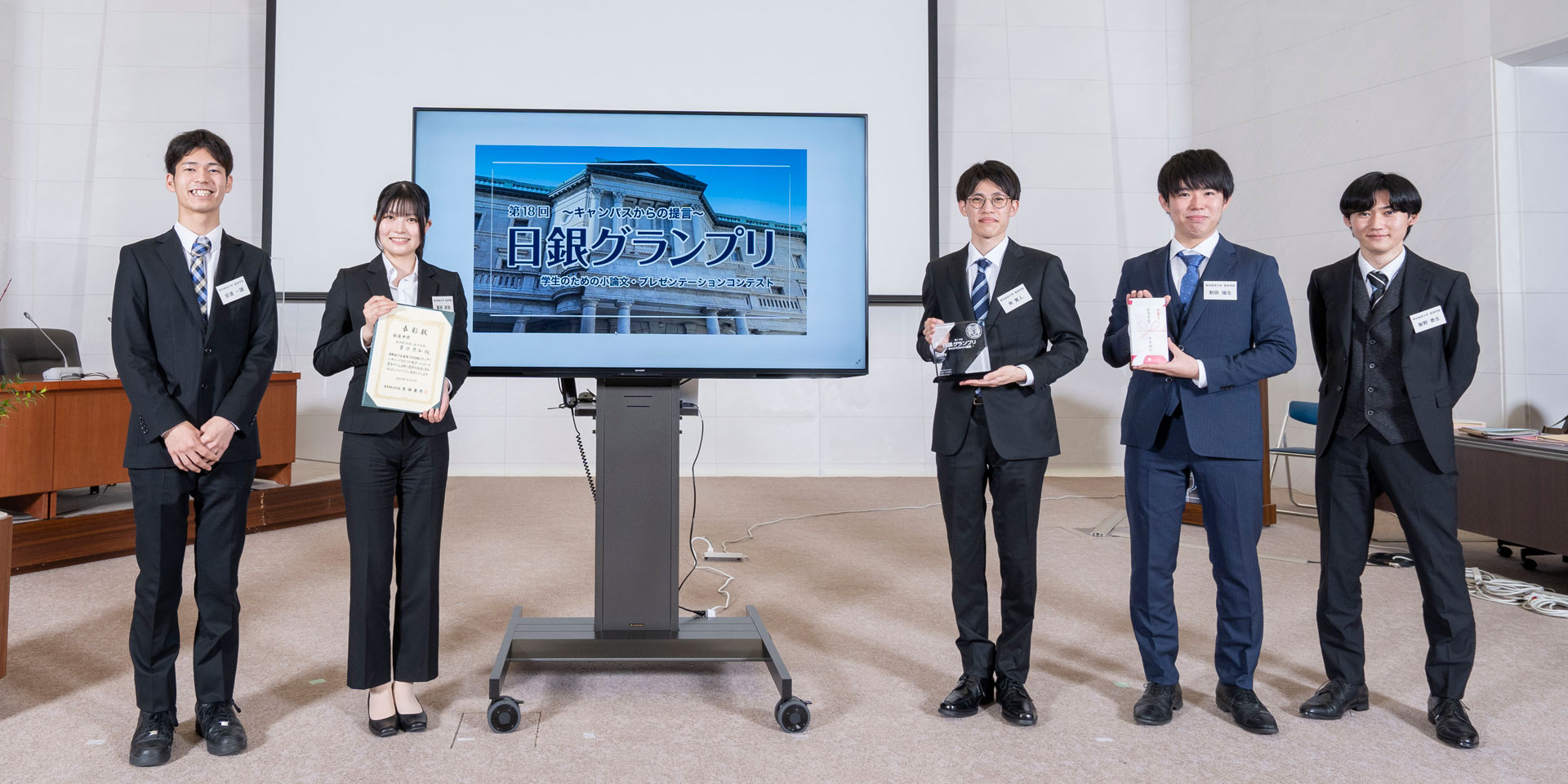 東京経済大学チームの学生5人が、横一列に起立して記念撮影している様子