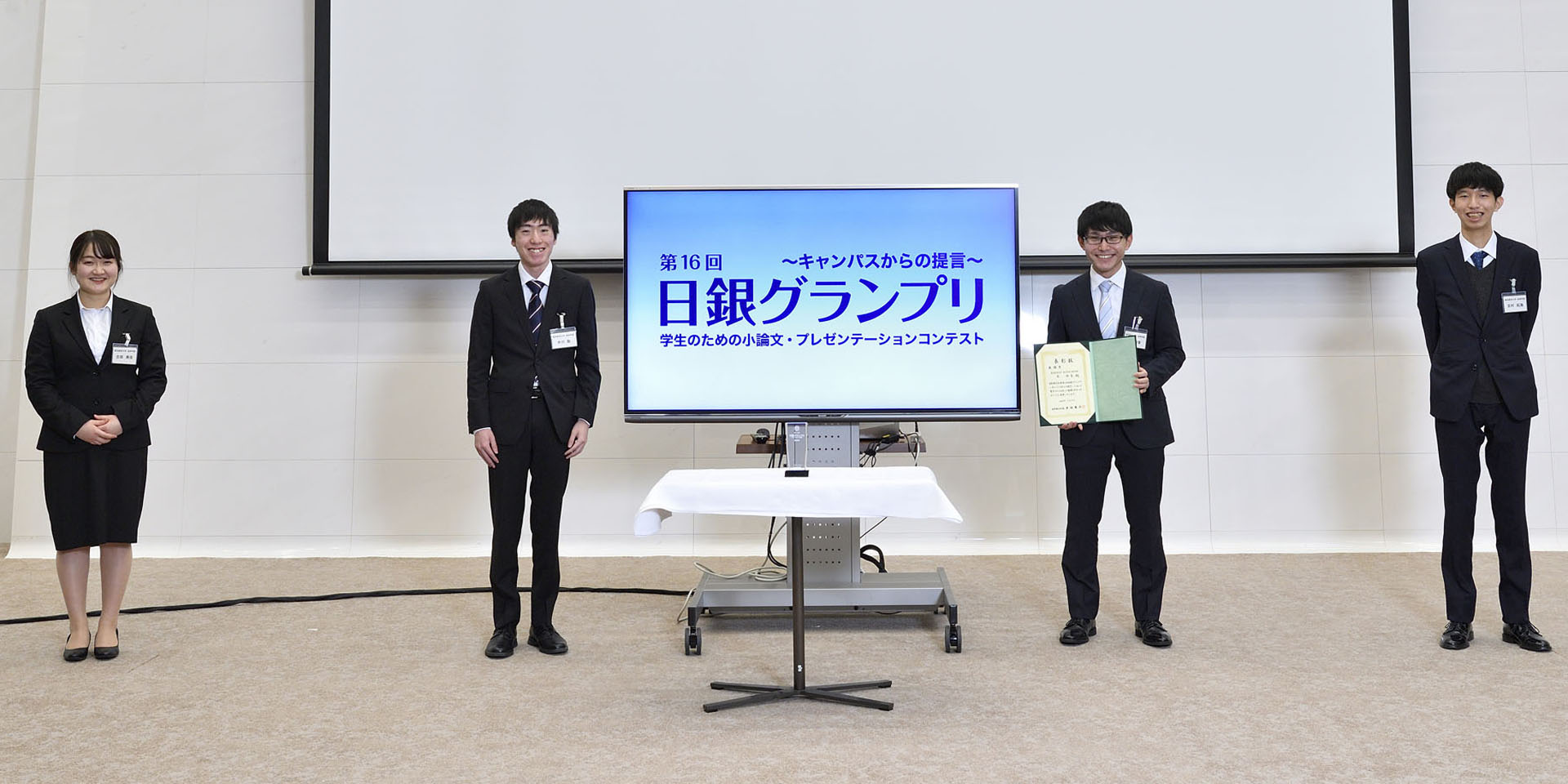 東京経済大学チームの学生4名が、間隔を空けて起立して記念撮影をしている様子