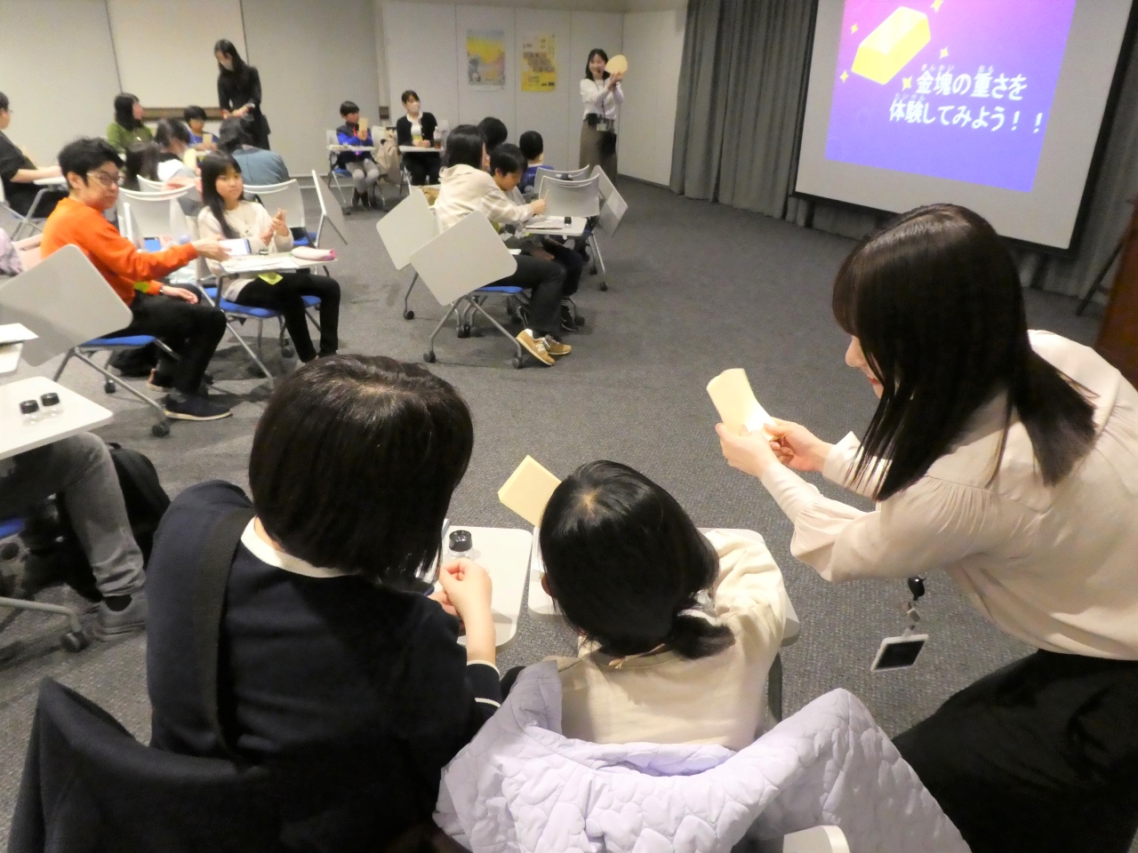 講師1人が、親子(母と娘)2人にお札の数え方を教えている様子