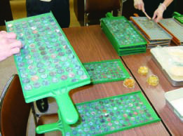 さびた硬貨を貨幣専用のマスに入れ確認する作業の写真