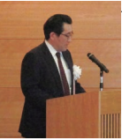 演台で説明している高野参事役の写真。