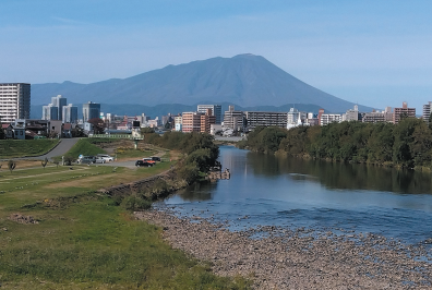 市街地の川から岩手山を望む写真。