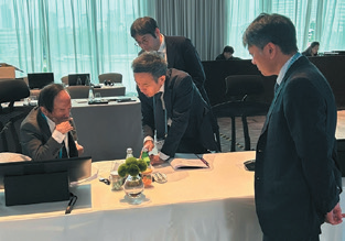 会議中の植田総裁を国際連携課の課員がサポートしている様子を撮影した写真。