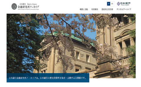 日本銀行金融研究所アーカイブのホームページにおけるトップページのスクリーンショット。ロゴマーク、メニュー、満開の桜ごしに日本銀行本店本館を捉えた写真のほか、「日本銀行金融研究所アーカイブは、日本銀行の歴史的資料を保存・公開する文書館です。」との説明文が表示されている。