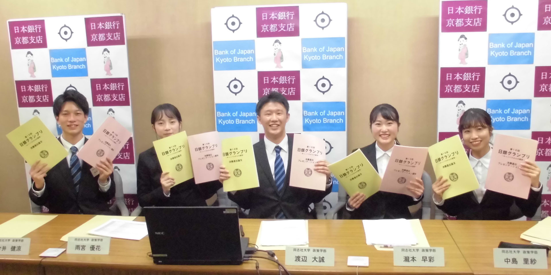 同志社大学チームの学生5名が、横一列に着席し、笑顔を向けている様子