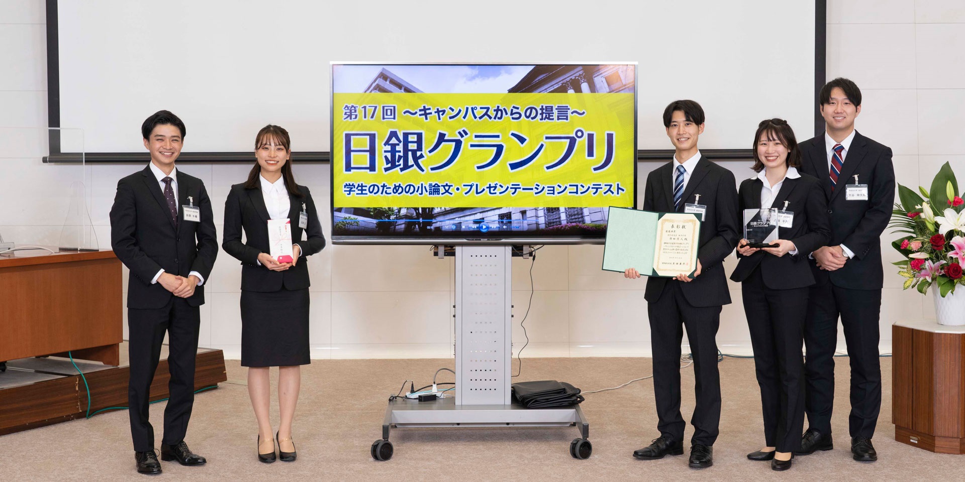 同志社大学チームの学生5人が、間隔を空けて横一列に起立して記念撮影している様子