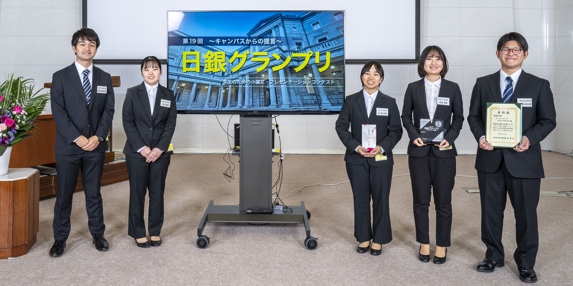 埼玉大学チームの学生5人が、横一列に起立して記念撮影している様子
