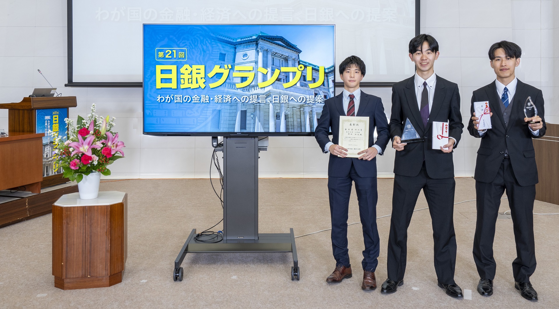 東京大学チームの学生3人が、横一列に起立して記念撮影している様子