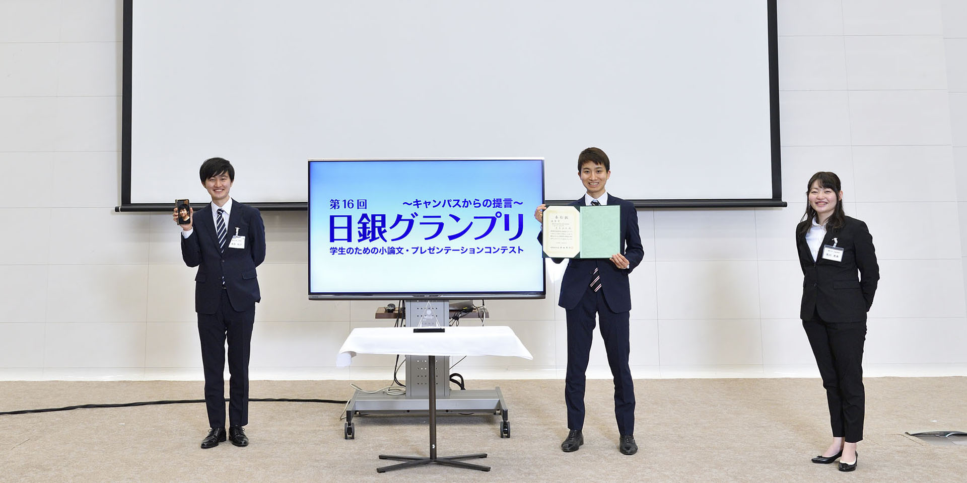 東京大学、一橋大学チームの学生3名が、間隔を空けて起立して記念撮影をしている様子