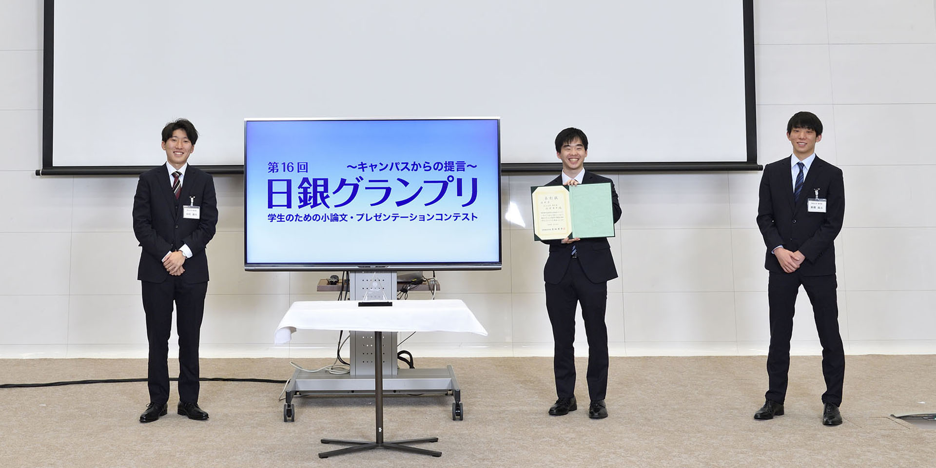 明治大学チームの学生3名が、間隔を空けて起立して記念撮影をしている様子