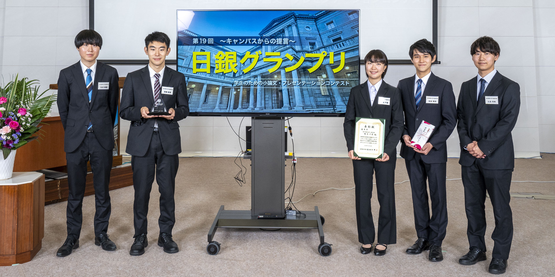 東京理科大学チームの学生5人が、横一列に起立して記念撮影している様子