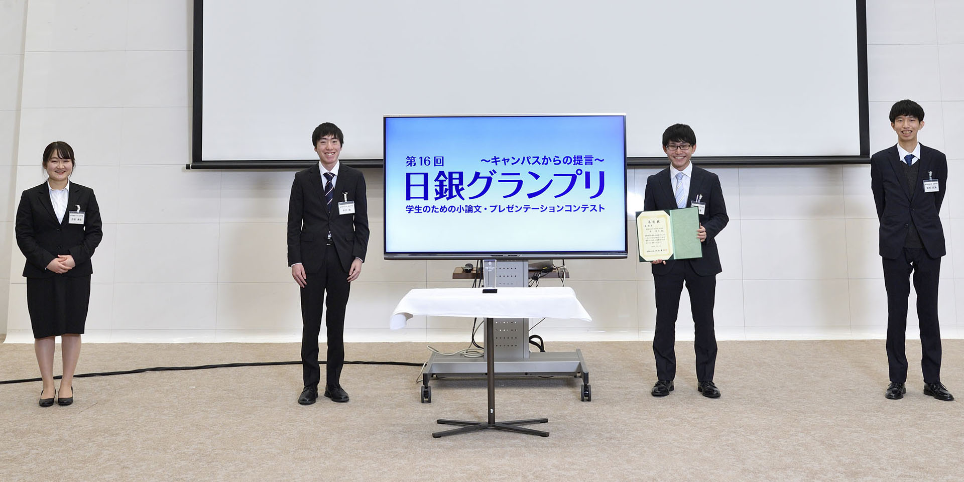 東京経済大学チームの学生4名が、間隔を空けて起立して記念撮影をしている様子