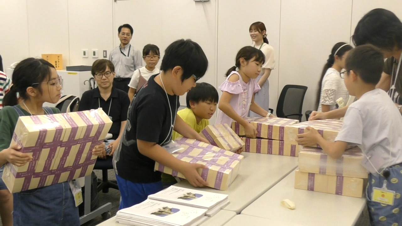 参加者5人が、一億円の重さ体験をしている様子