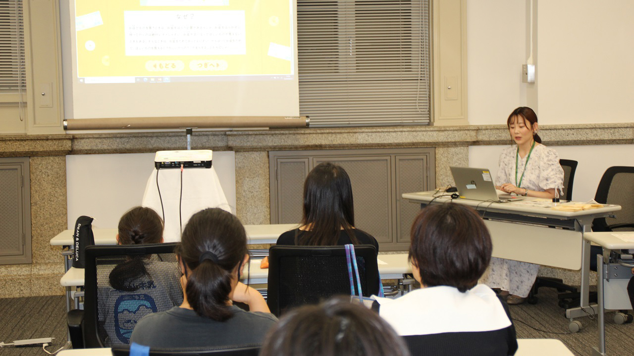 講師1人が、参加者20人に向かってお金の使い方に関する講義をしている様子