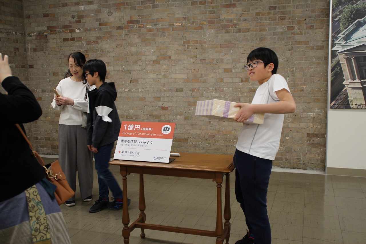 参加者1人が、一億円の重さ体験をしている様子