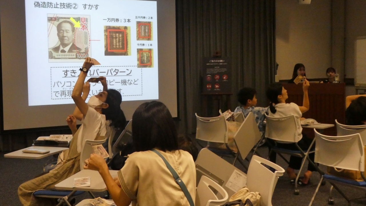 参加者6人が、お札を傾けてすき入れ模様を確認している様子