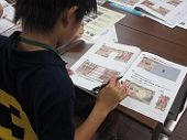 子どもが、破れたお札の引換の仕事を練習問題を使って体験している写真
