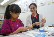 子どもがお札の裁断屑が入った「オリジナルしおり」を作成している写真