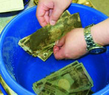泥まみれの紙幣を確認する作業の写真