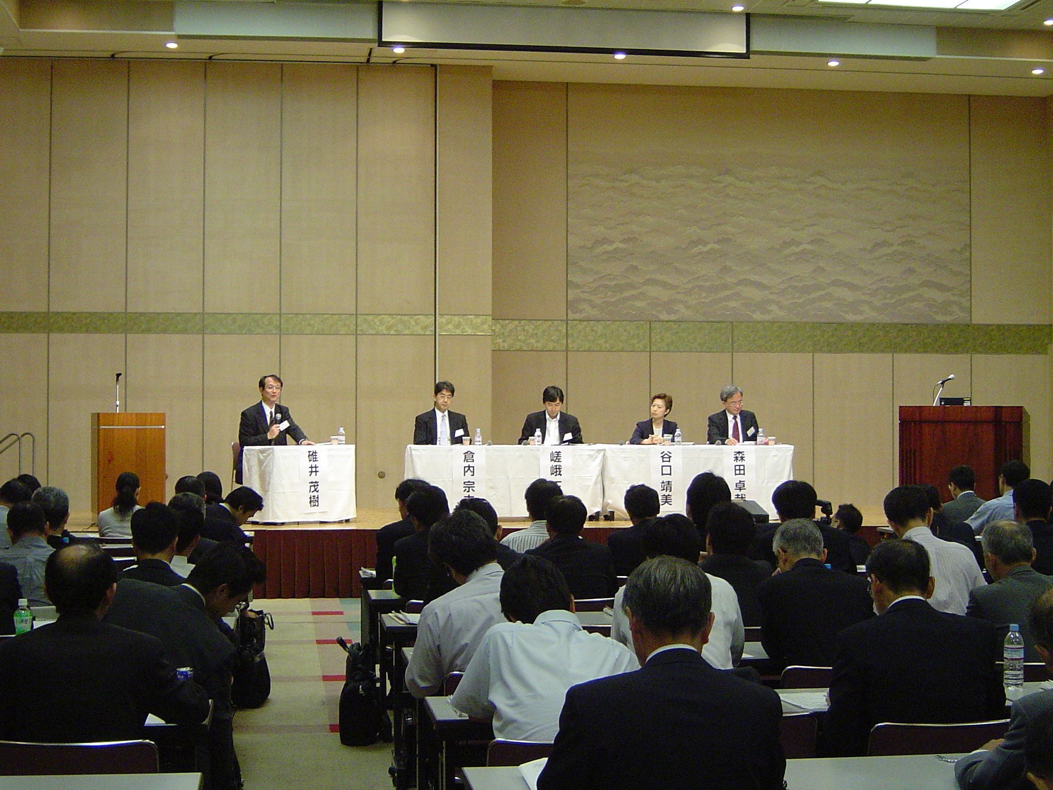 壇上に座っているパネリストとセミナー参加者を会場の後方から撮影した写真