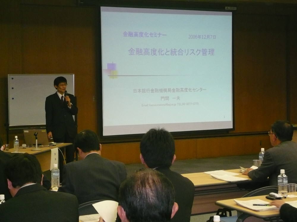壇上でパネリストが左手にマイクを持って講演をしている写真